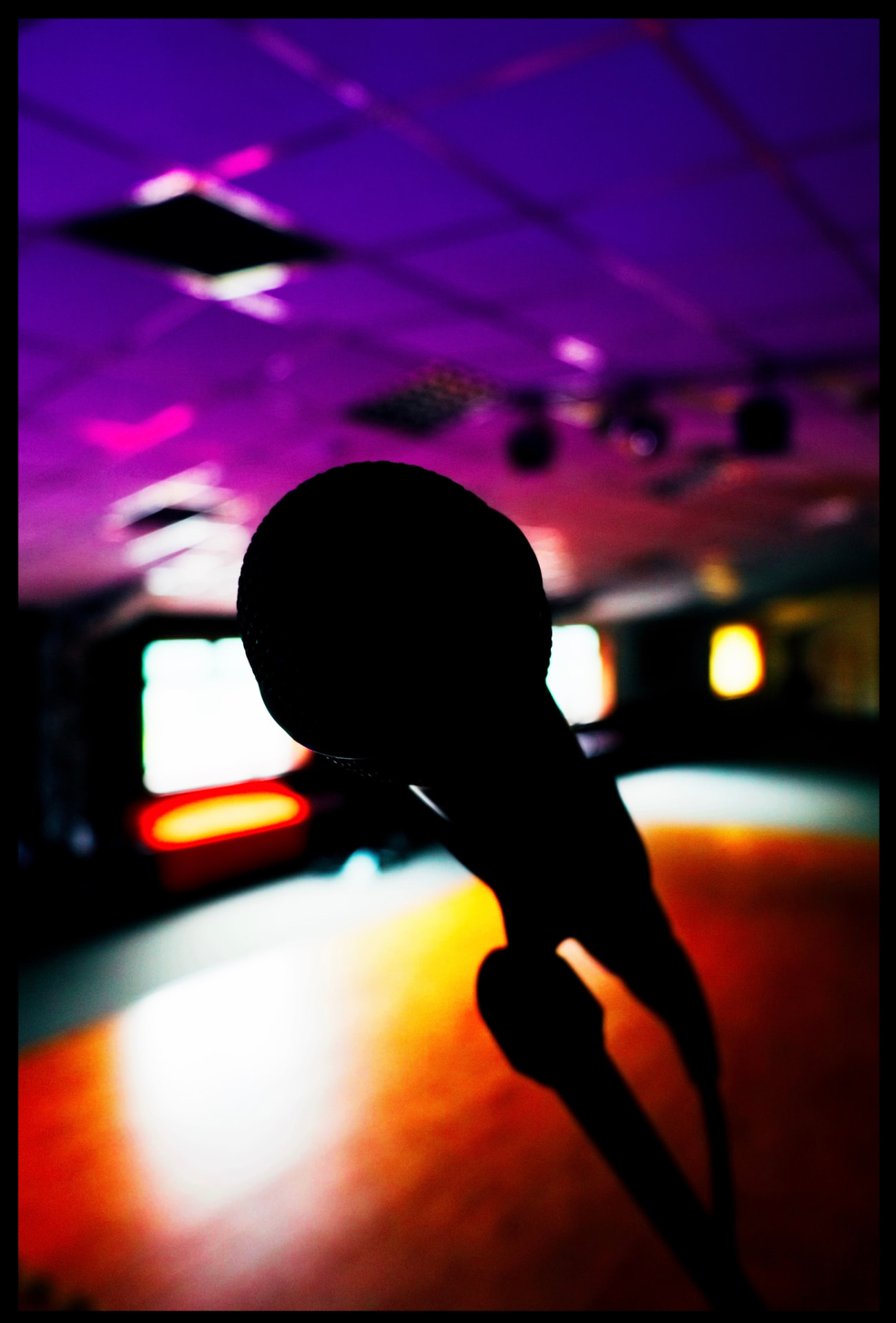 A microphone on stage under purple and orange stage lighting at New Imp Studio