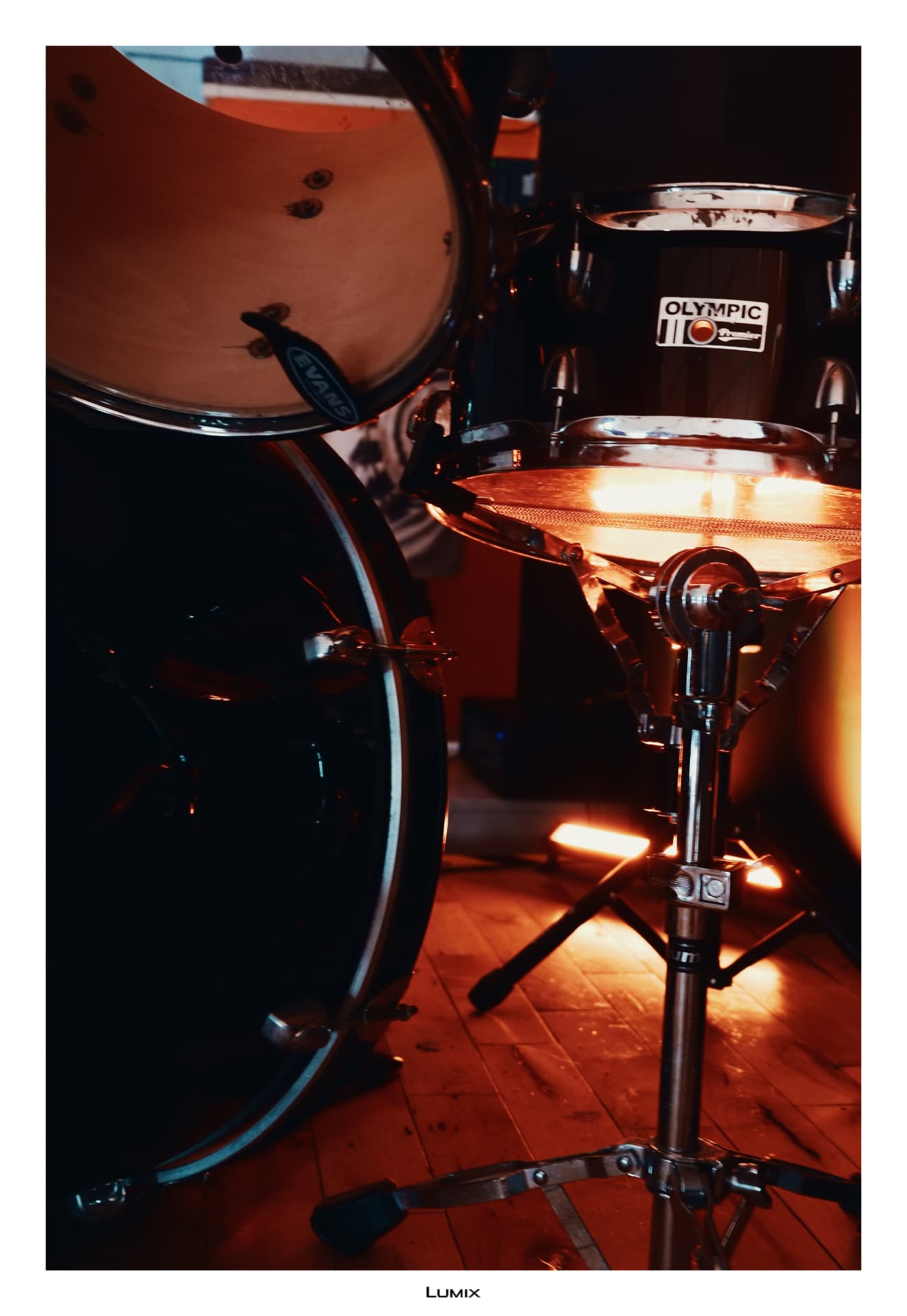 A drum kit lit in warm amber light on the New Imp Studio stage